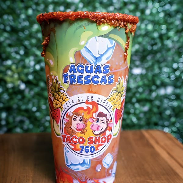 Agua Fresca drink from Taco Shop 760, with a chili-rimmed cup and green background.
