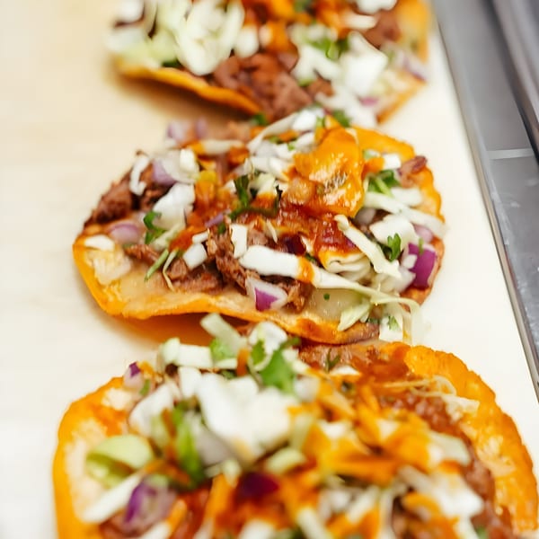 Three delicious Taco Shop 760 tostadas topped with meat, cabbage, onions, and sauce.